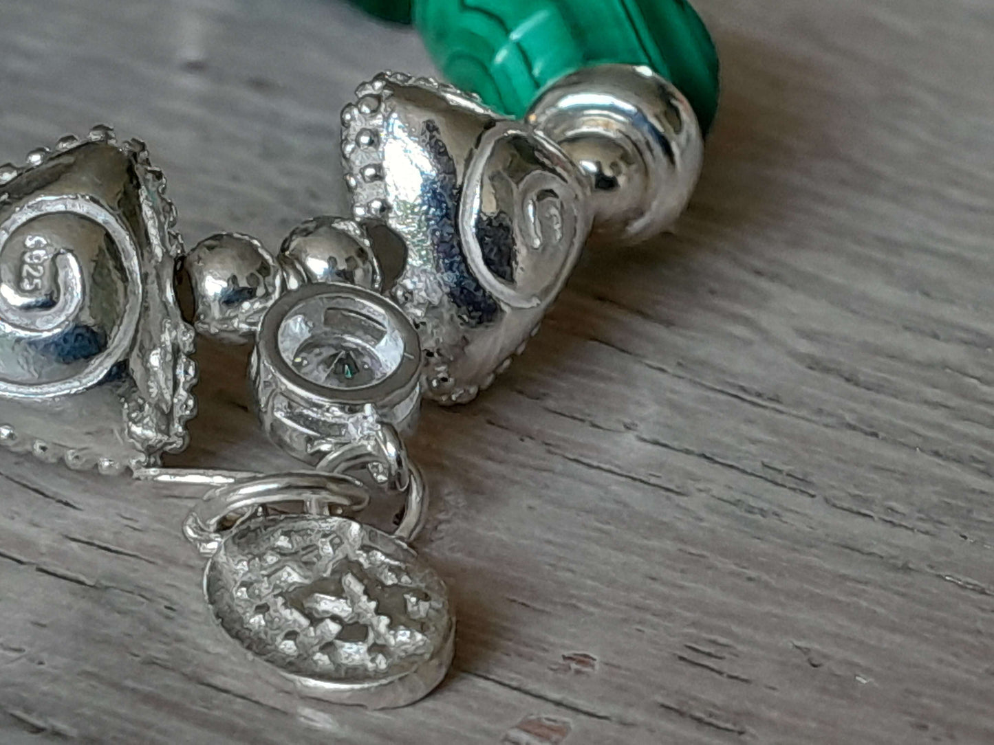 Close-up of a malachite bracelet featuring sterling silver detailing and intricate bead designs.